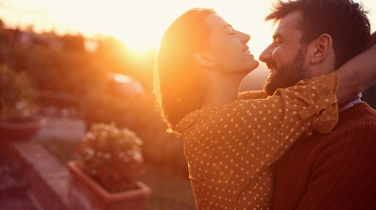 Frau und Mann schauen sich verliebt an bei Sonnenuntergang