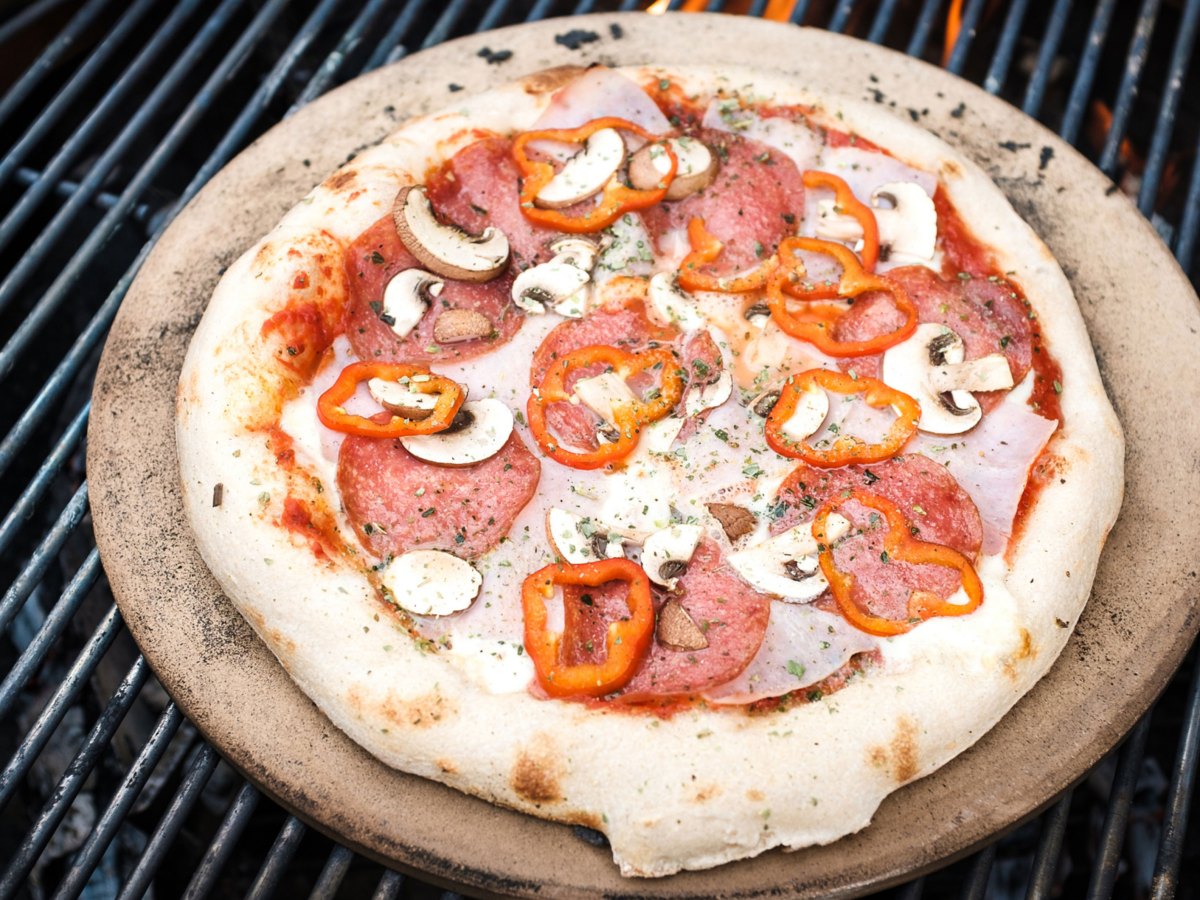 Pizza auf einem Pizzastein auf einem Grill