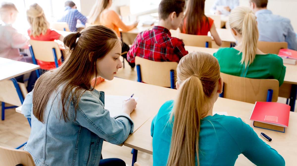 Klassenraum mit Schülerinnen und Schülern, die gerade an zweier Teamaufgaben sitzen.