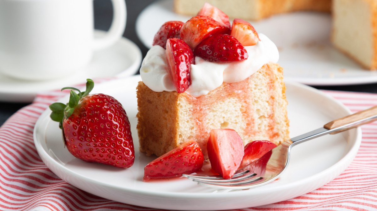 Angel Food Cake mit Erdbeeren und Sahne auf weißem Kuchenteller.