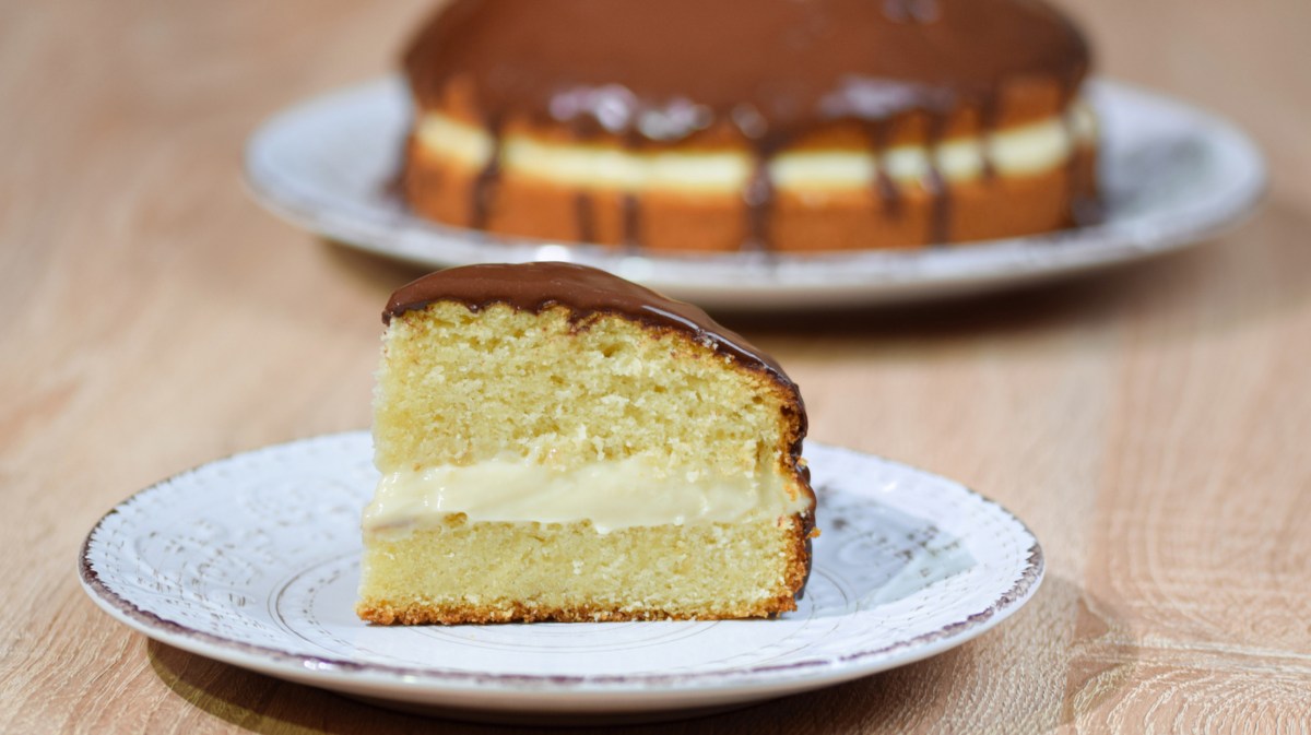 Boston Cream Pie auf einem hellen Kuchenteller.