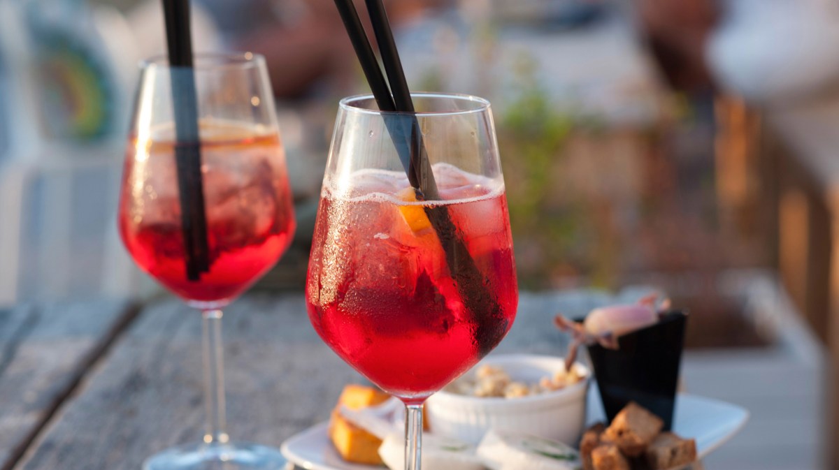 Lillet Ruby Cocktail in einem Glas auf einem Terrassentisch.