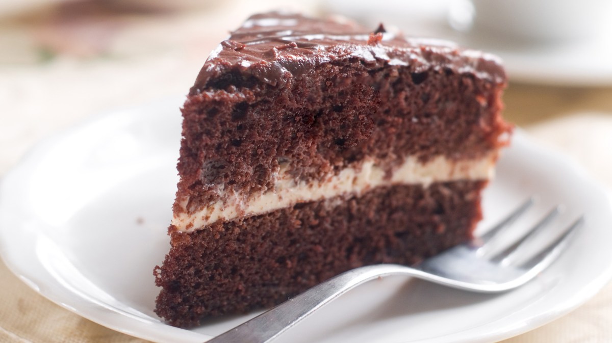 Schokotorte mit Sahne in der Mitte auf einem weißen Teller.