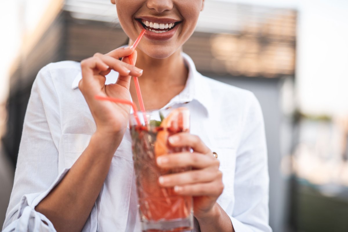 Frau hält Cocktail in der Hand und lächelt
