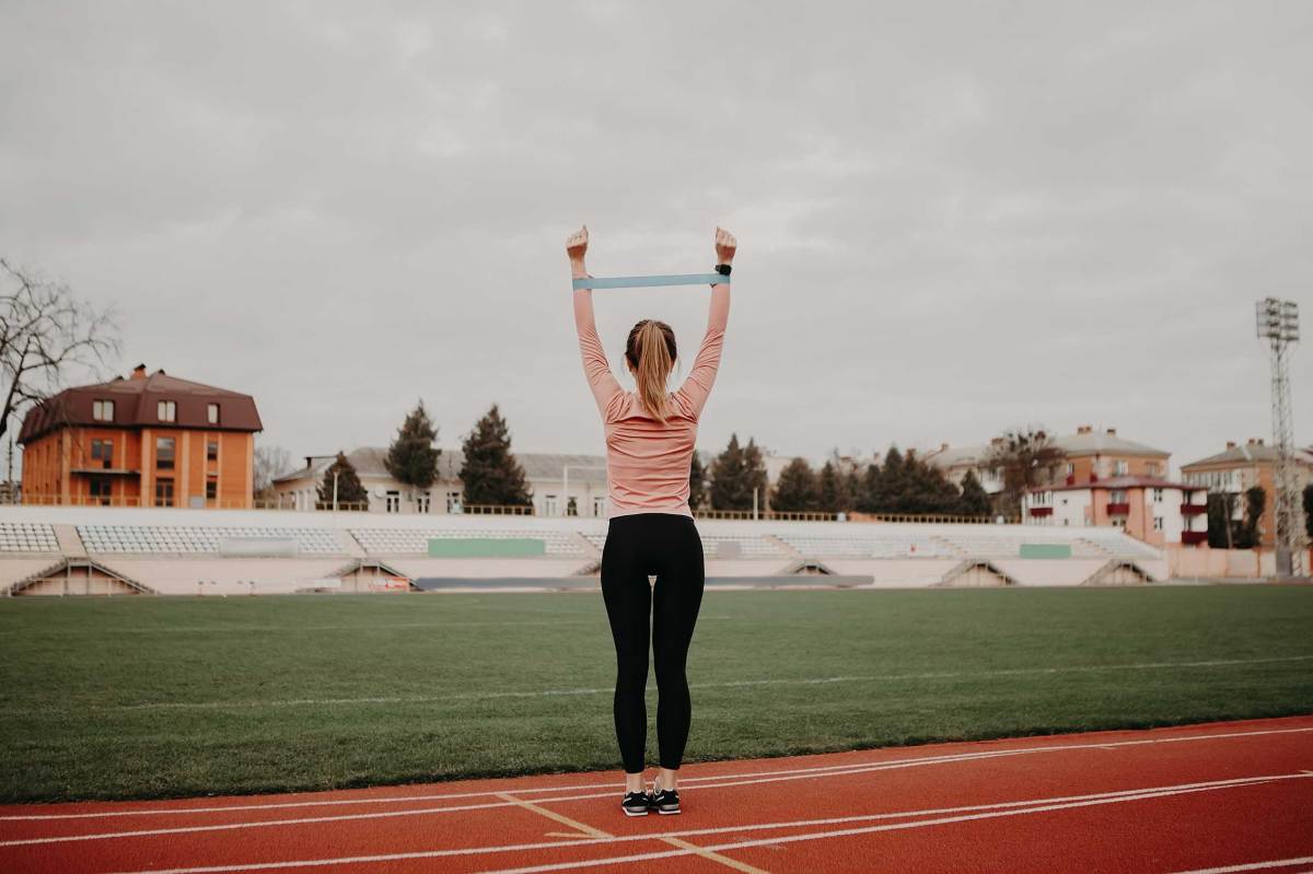 Sportliche Frau macht Übung mit Widerstandsband. Weibliche Athletin arbeitet an ihrer Fitness.