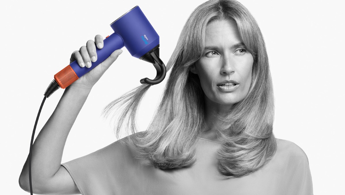 Model hält den neuen Supersonic Nural Föhn von Dyson in der Hand.