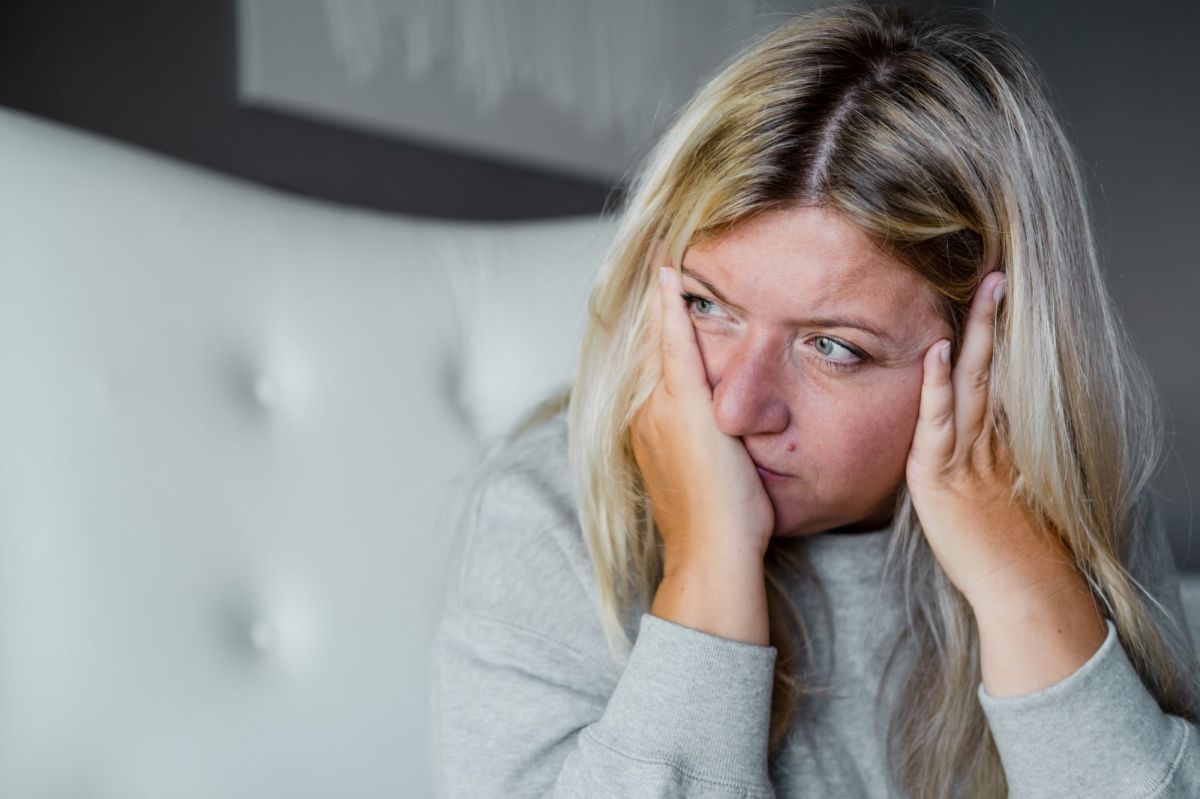 Frau hält sich die Hände ans Gesicht und sieht gestresst aus als Symbolbild für das Thema "Cortisol zu hoch Symptome Frau"