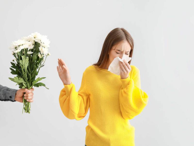 Frau mit Allergie lehnt Blumen ab, die ihr von einem Mann angeboten werden.