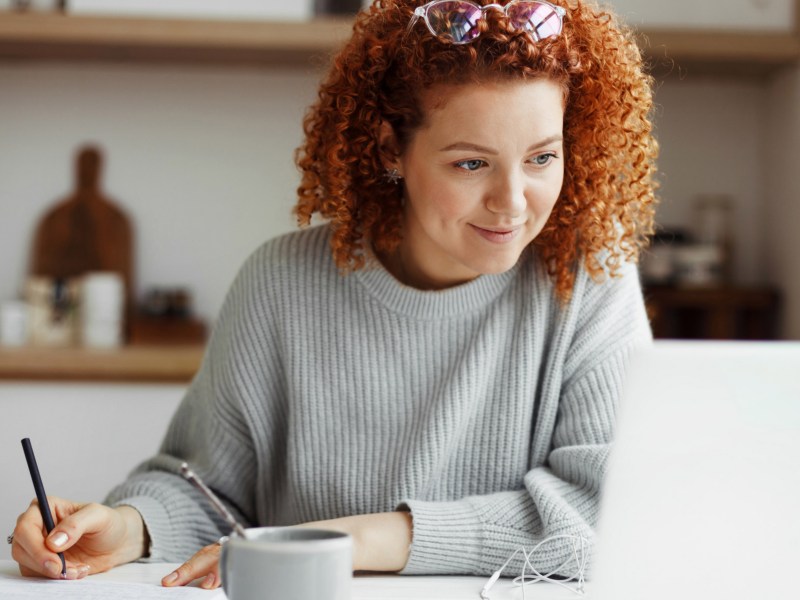 Frau mit roten Locken schaut auf Laptop.