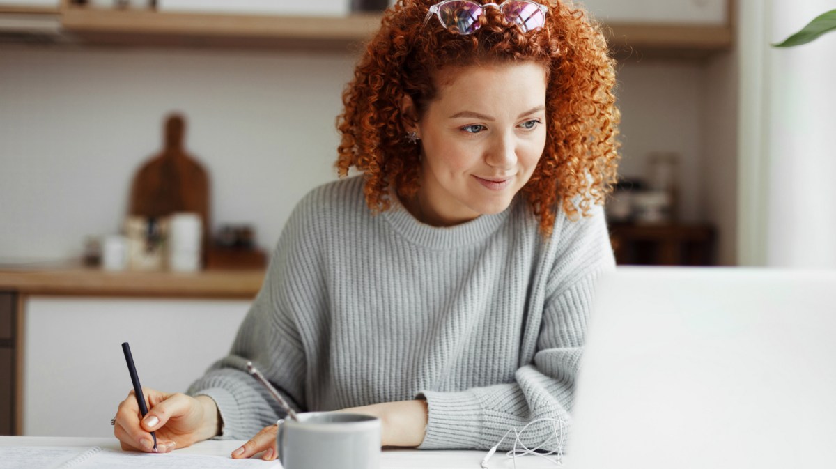 Frau mit roten Locken schaut auf Laptop.