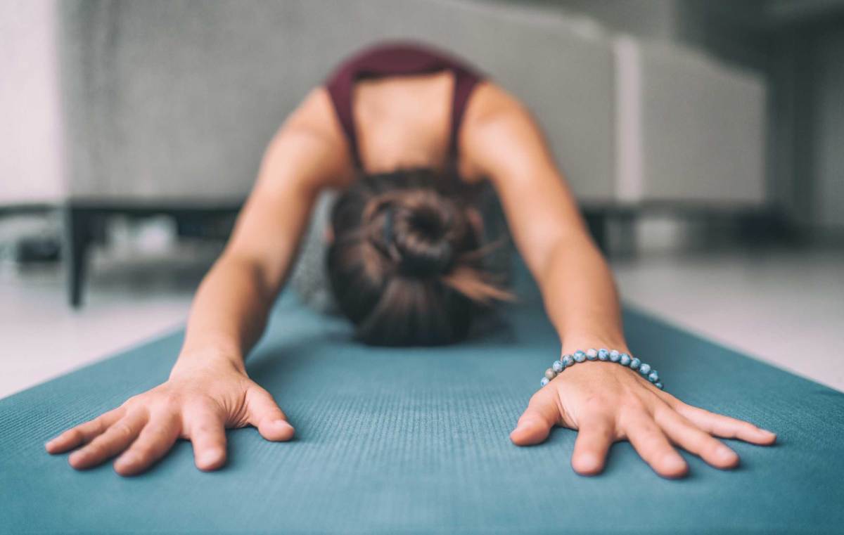 Yoga zu Hause, Stretching, Meditation Frau macht Kinder Pose. Hände berühren Boden Übungsmatte und Mala-Armband. Fitness, Entspannung, stressfrei