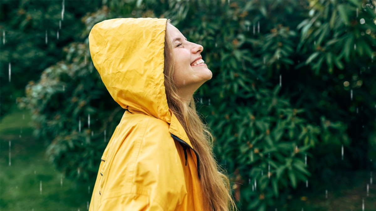 Frau, die im Regen tanzt und nach oben schaut