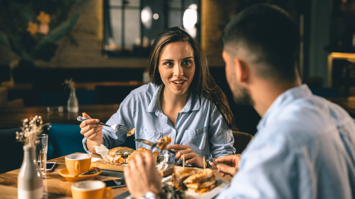 Frau und Mann beim Essen, die sich miteinander unterhalten.