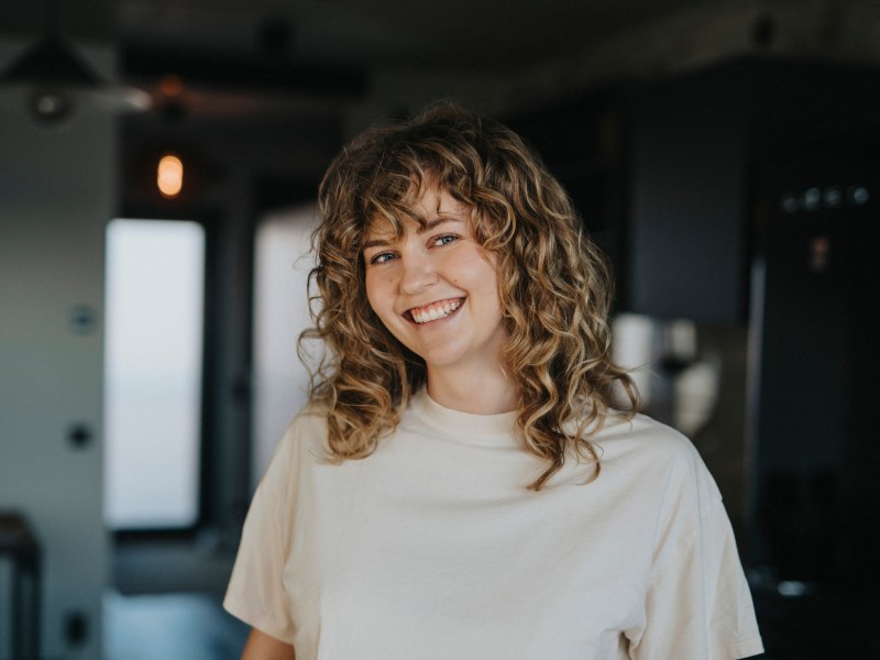 Frau mit blonden Locken lacht in die Kamera