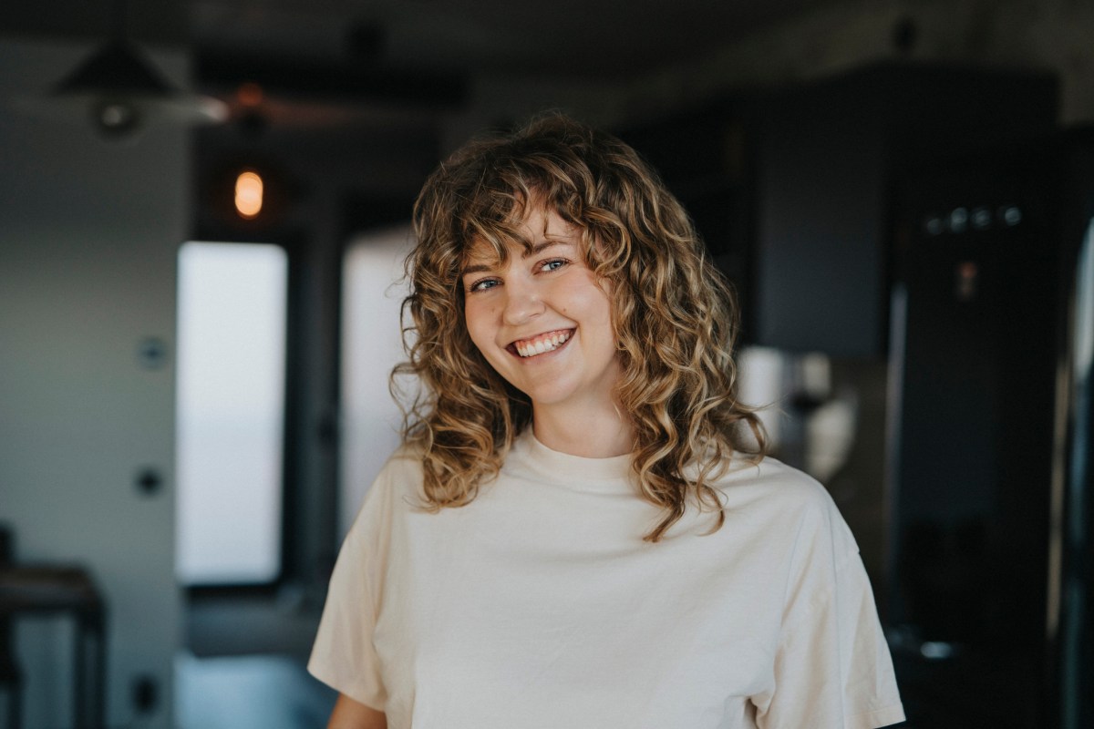 Frau mit blonden Locken lacht in die Kamera