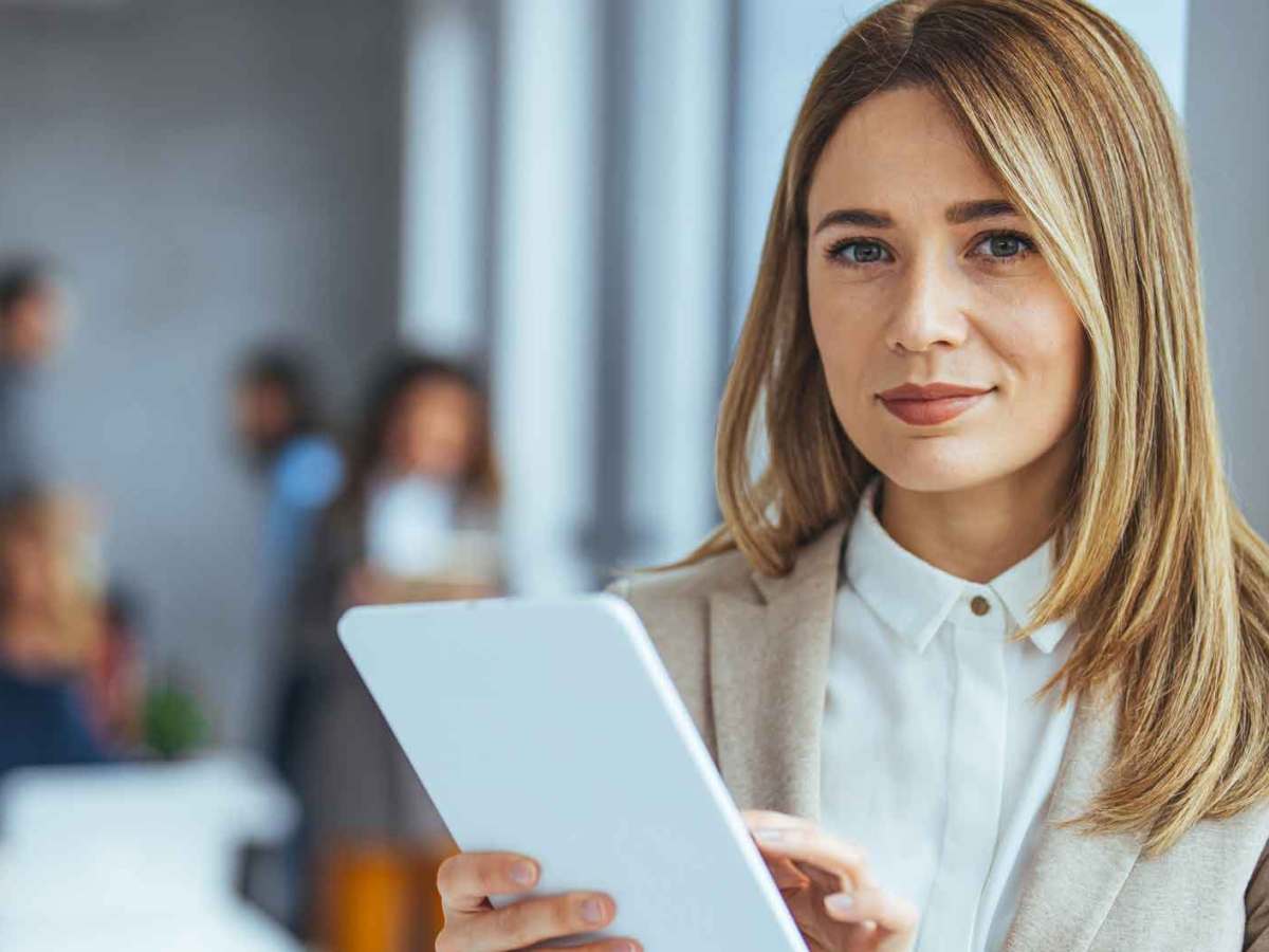 Blonde Frau steht im Büro und liest ein Schreiben.