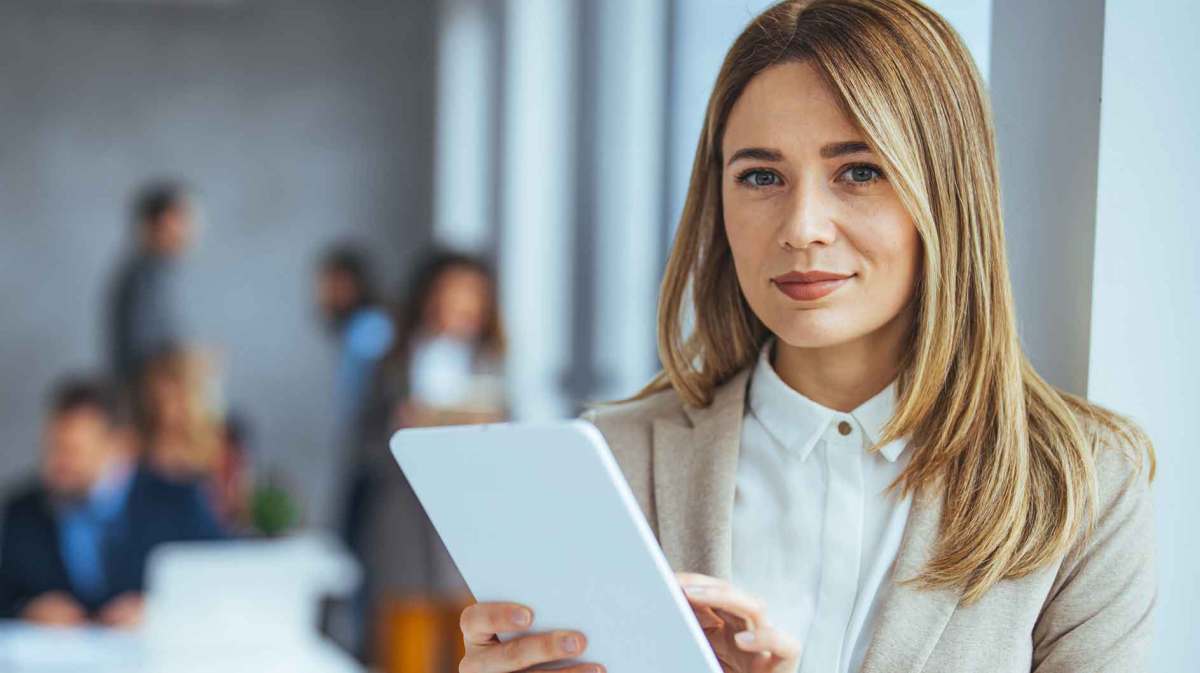 Blonde Frau steht im Büro und liest ein Schreiben.