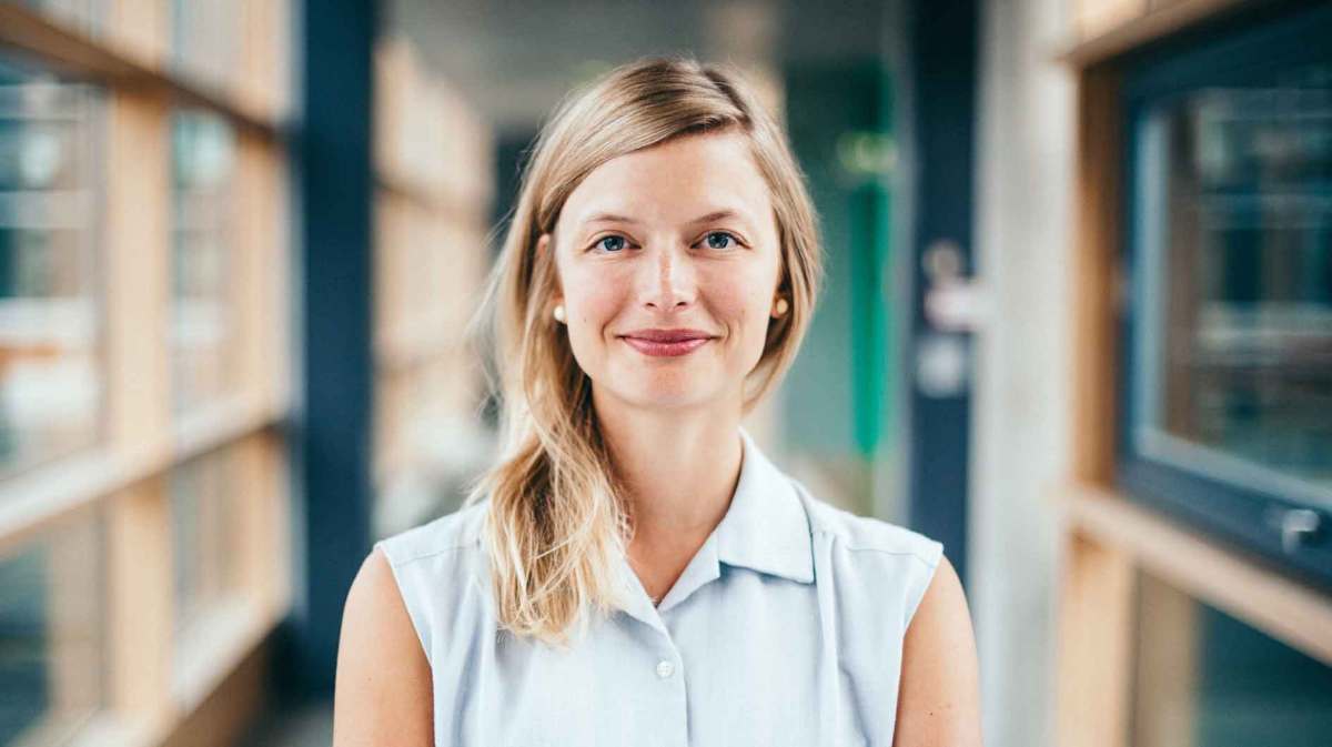 Junge Frau mit blonden Haaren steht im Büro.