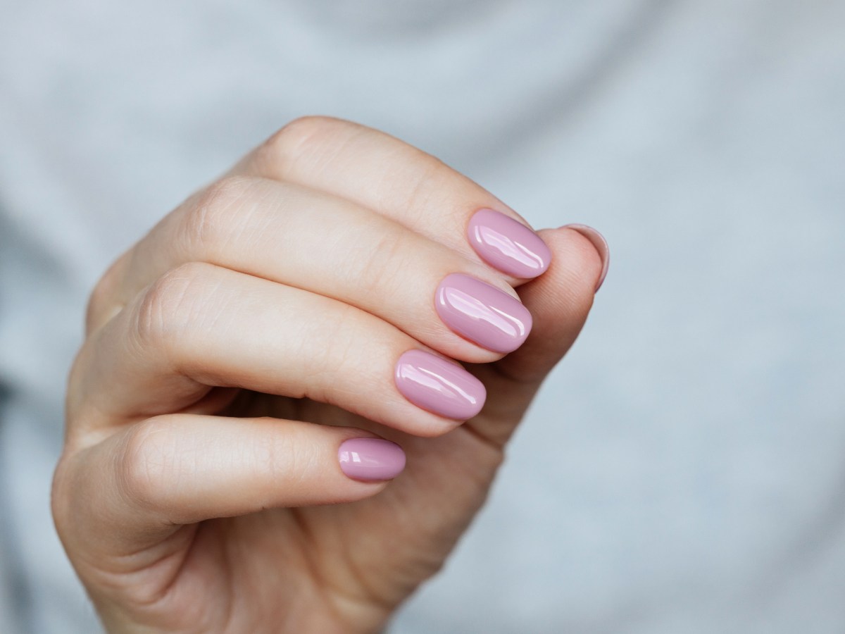 Frau mit rosa lackierten Fingernägeln