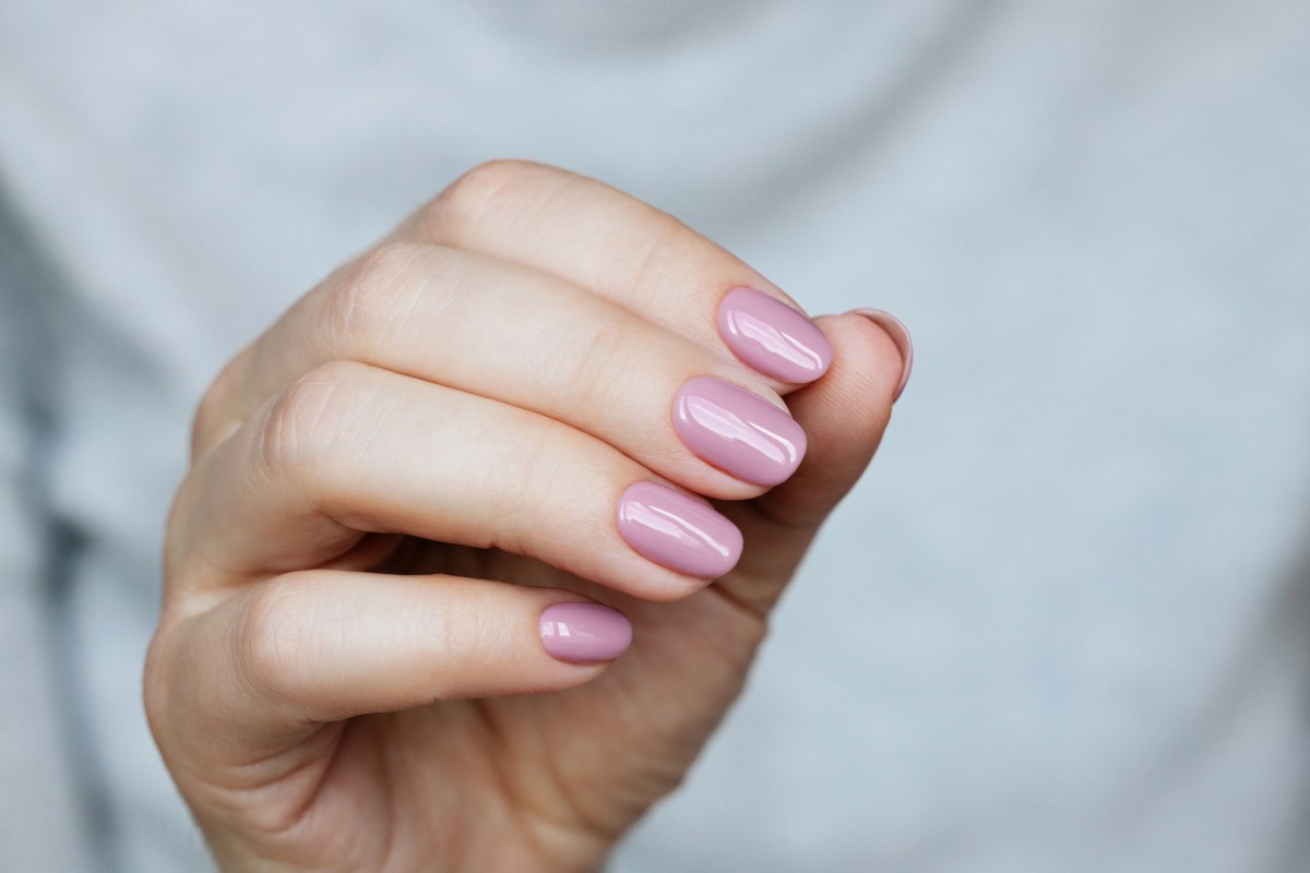 Frau mit rosa lackierten Fingernägeln