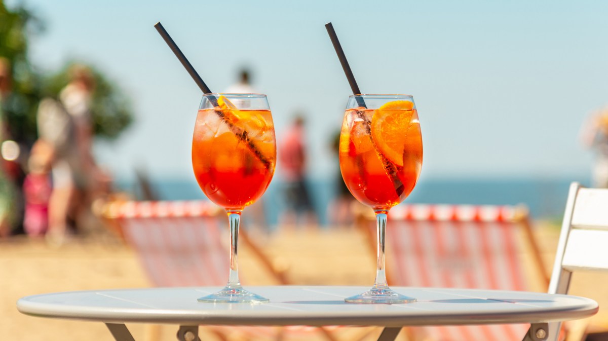 Zwei Cocktailgläser auf Tisch vor sommerlichem Hintergrund.