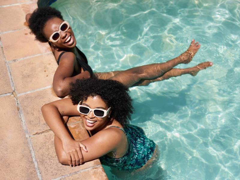 Zwei schöne Frauen kühlen sich im Schwimmbad ab, Hitzewelle im Sommer