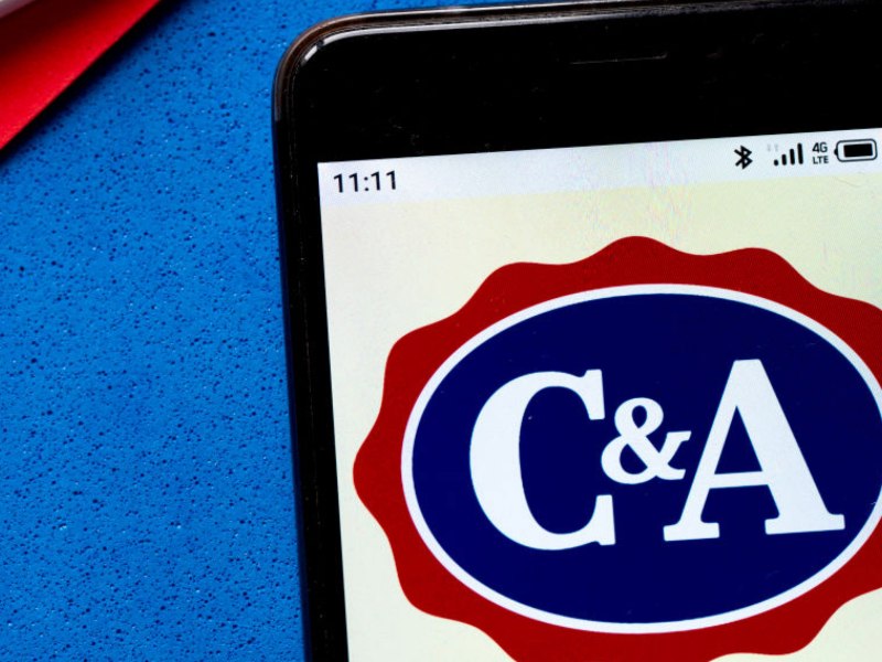 C&A Logo auf einem Handy, das auf blauem Untergrund liegt.