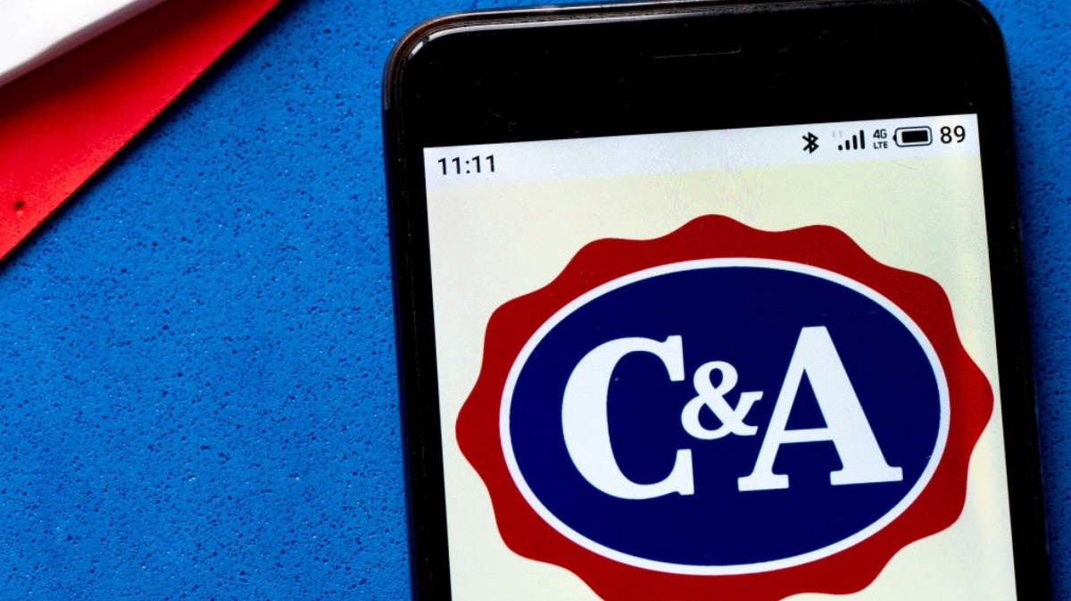 C&A Logo auf einem Handy, das auf blauem Untergrund liegt.