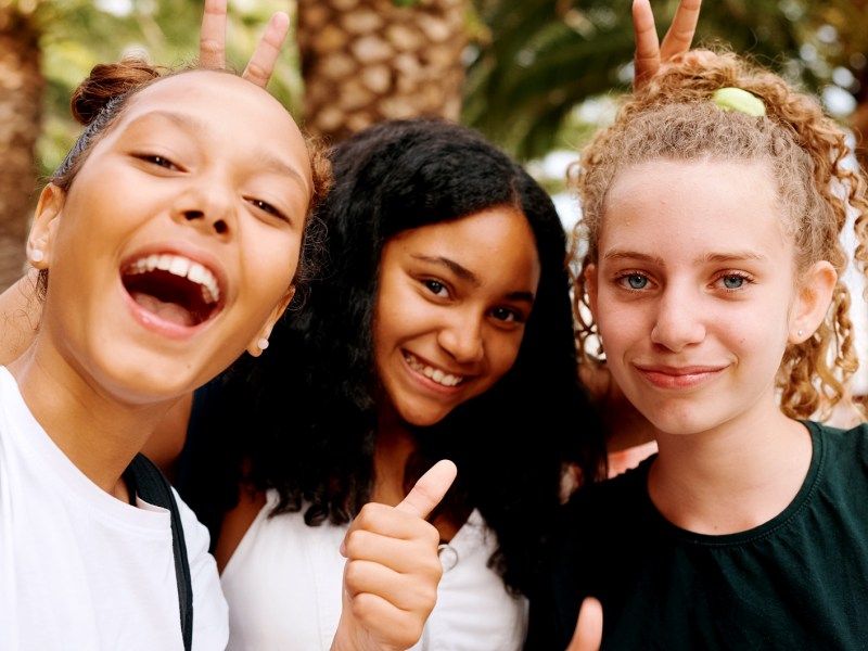 Drei Mädchen, zwischen 12 und 14 Jahren, posieren cool und albern und machen ein Selfie.