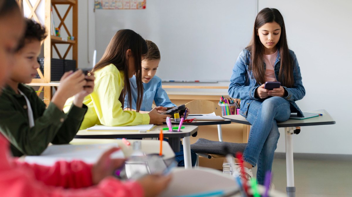 Gruppe von Schülern im Klassenzimmer. Alle hängen einzeln am Handy, es findet kein Austausch zwischen ihnen statt.