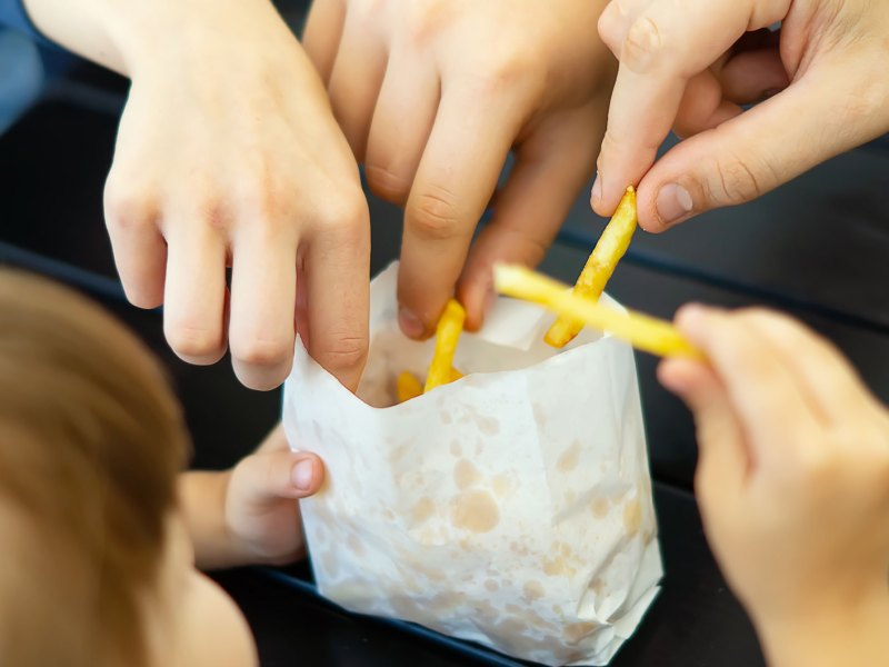 Familie isst zusammen eine kleine Portion Pommes.