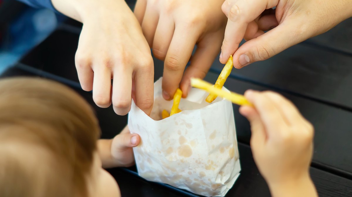 Familie isst zusammen eine kleine Portion Pommes.