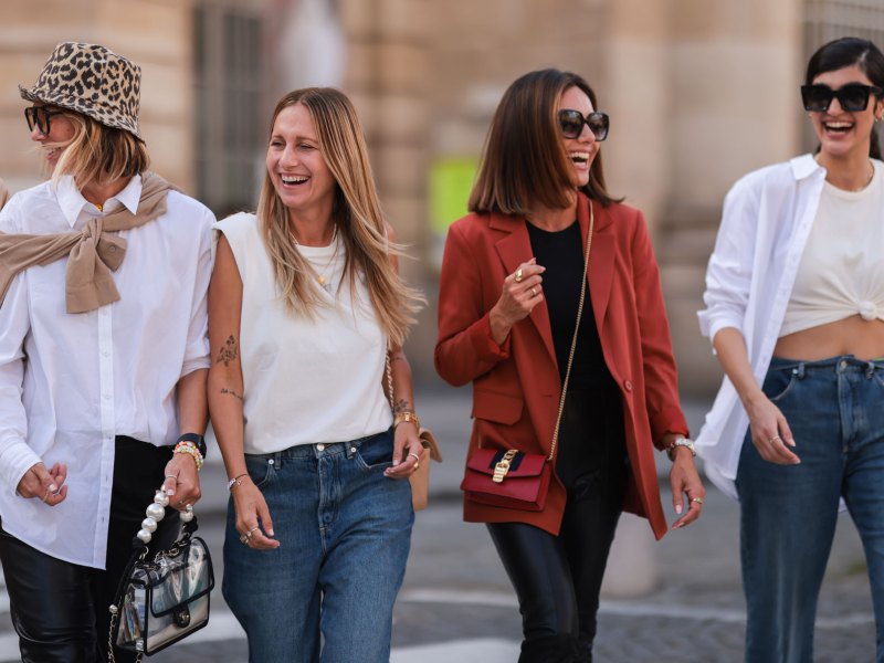 Gruppe von 5 stylischen Frauen lacht auf der Straße