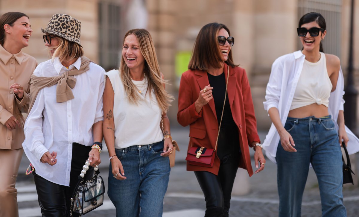 Gruppe von 5 stylischen Frauen lacht auf der Straße