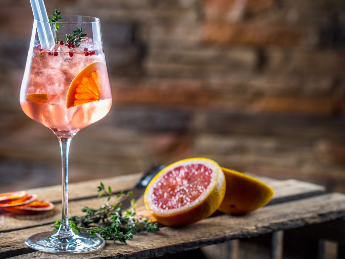 Cocktailglas mit Grapefruitscheibe darin auf Holztisch.