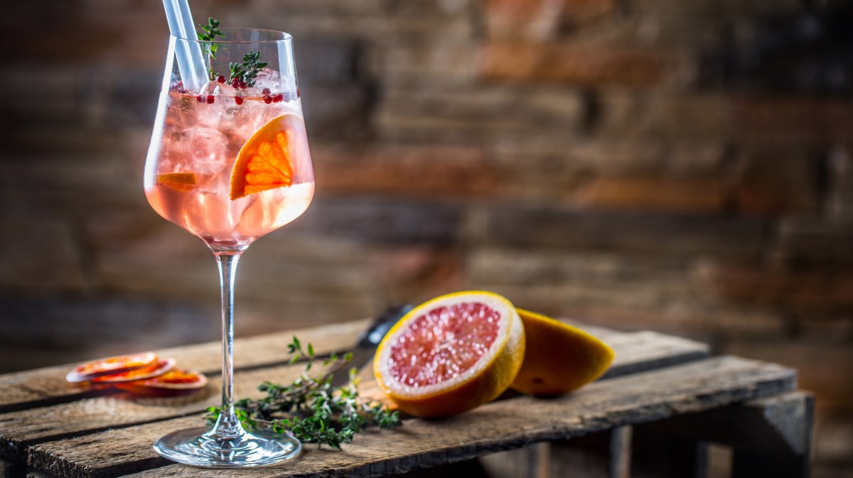 Cocktailglas mit Grapefruitscheibe darin auf Holztisch.