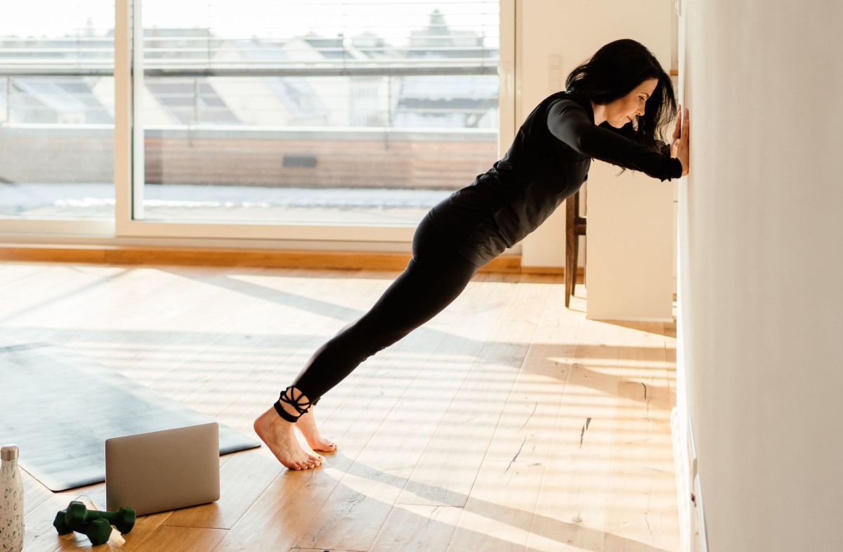 Wand Pilates Übungen: Frau in schwarzer Trainingskleidung macht Wall Push up