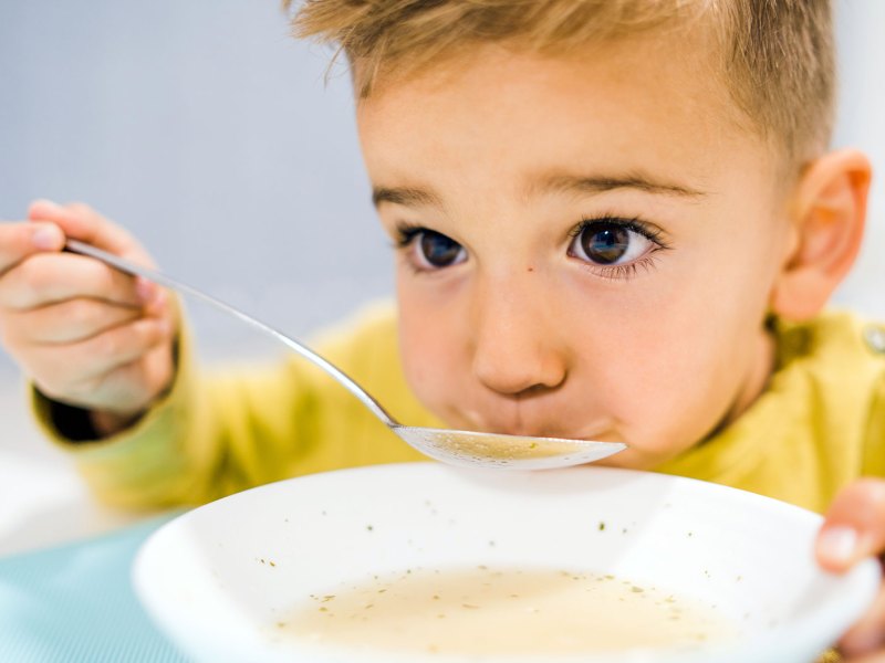 Nahaufnahme eines Jungen, ca. 6 Jahre alt, der bedächtig eine Suppe löffelt.