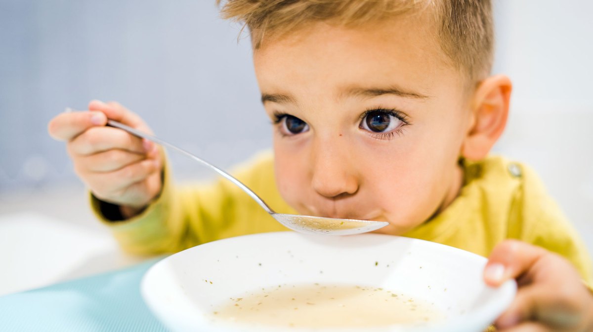 Nahaufnahme eines Jungen, ca. 6 Jahre alt, der bedächtig eine Suppe löffelt.