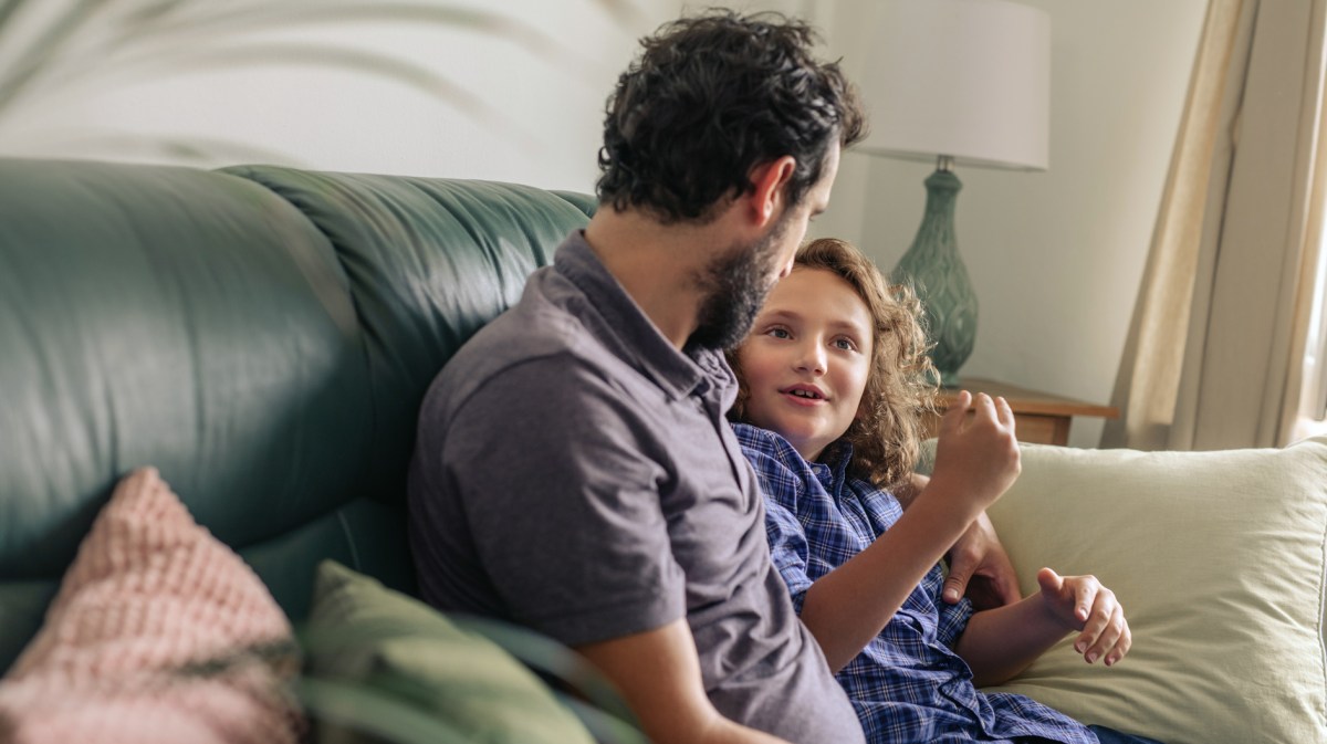 Vater und Kind sitzen auf dem Sofa und quatschen ganz entspannt.