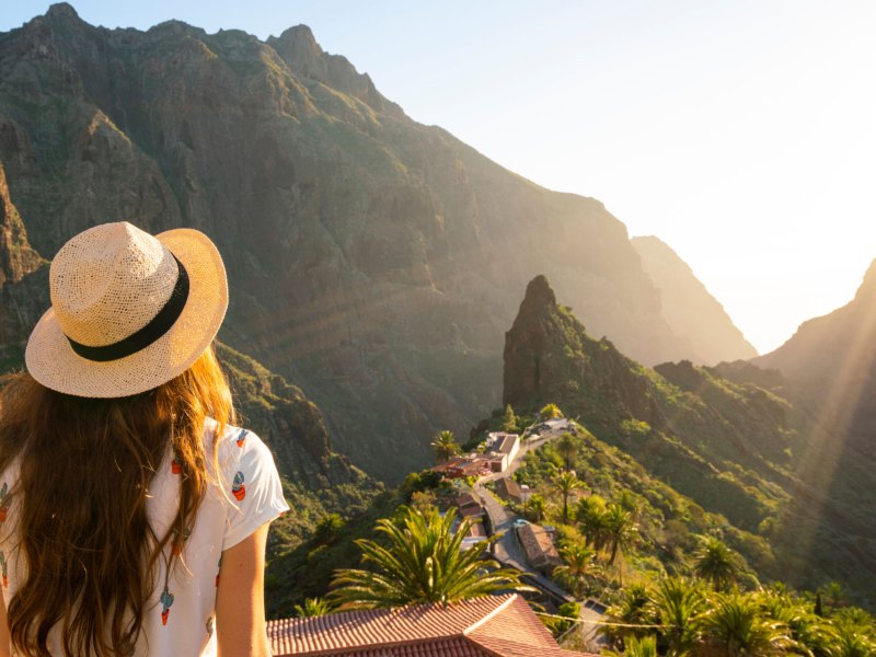 Frau mit Sonnenhut schaut in die Ferne des Masca Village, Teneriffa.