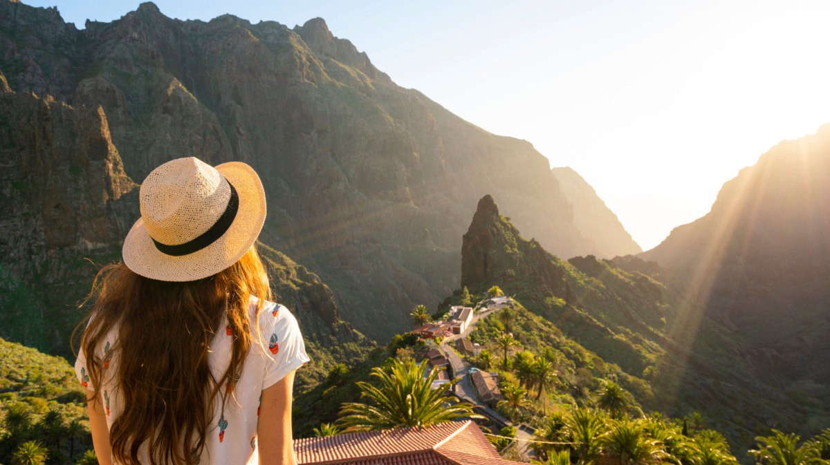 Frau mit Sonnenhut schaut in die Ferne des Masca Village, Teneriffa.