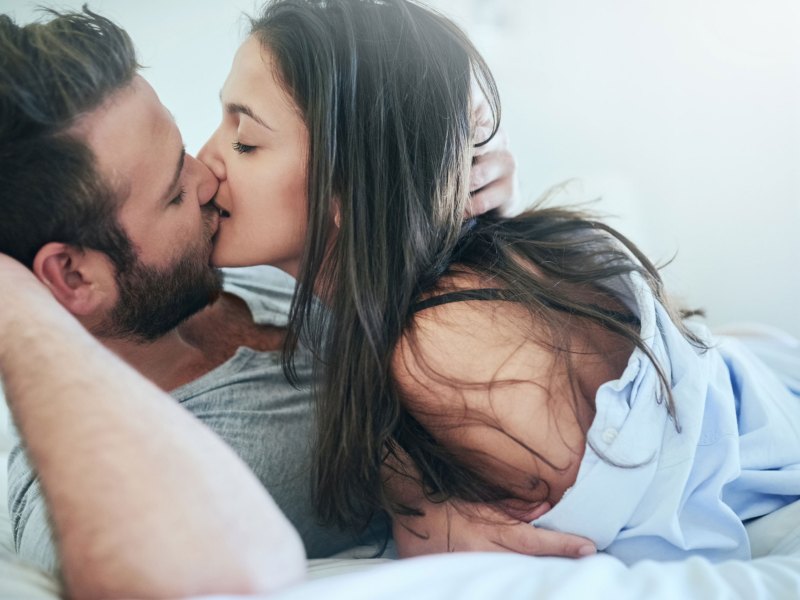 Mann und Frau küssen sich zärtlich im Bett