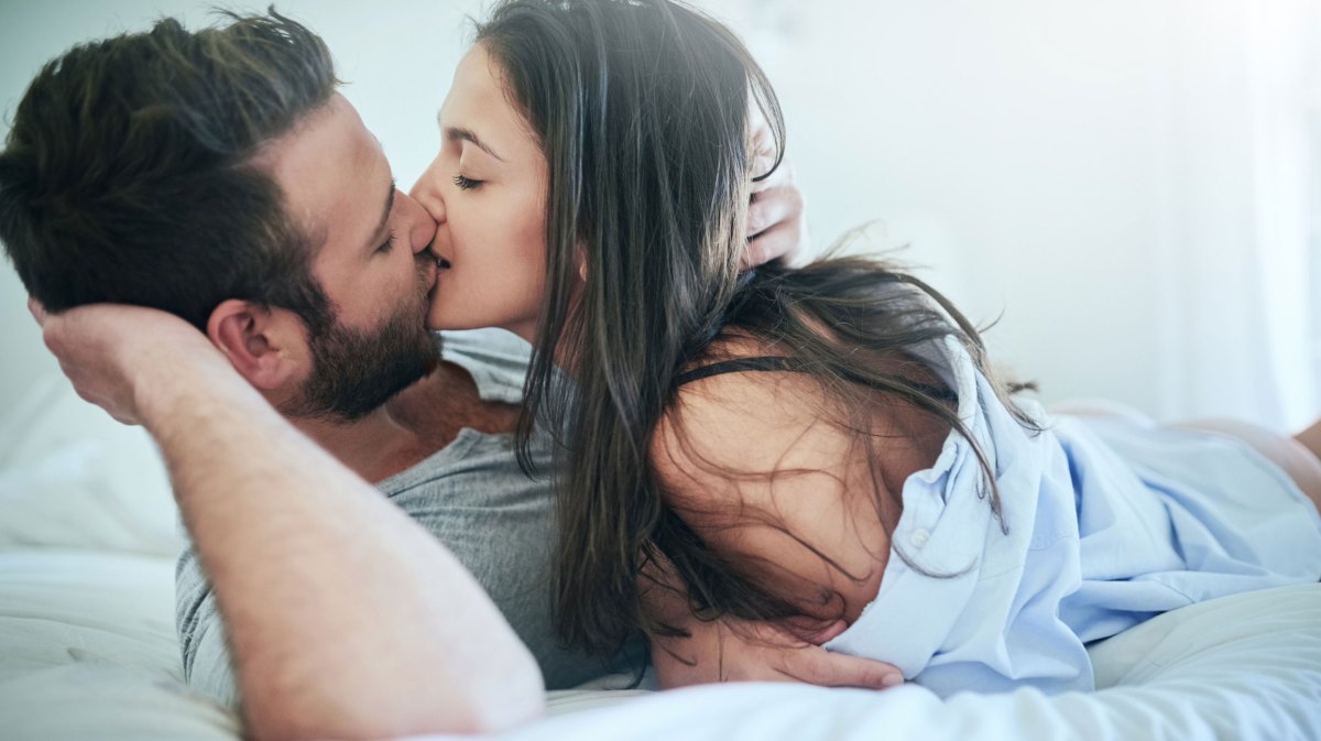 Mann und Frau küssen sich zärtlich im Bett