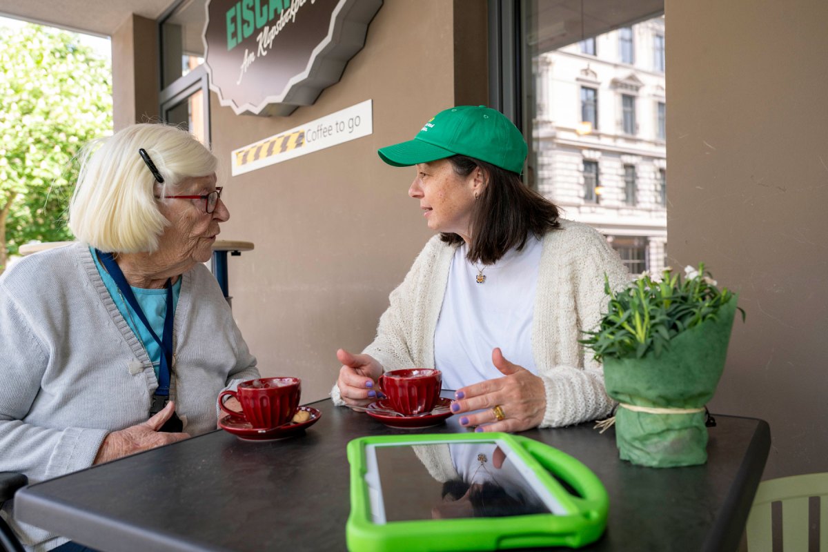 Jüngere Frau sitzt mit einer Seniorin am Tisch