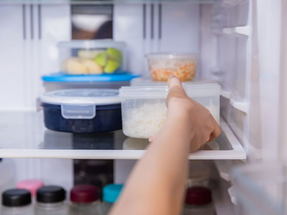 Eine Person stellt Plastikdosen mit Essen in den Kühlschrank