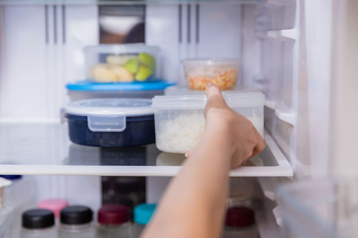 Eine Person stellt Plastikdosen mit Essen in den Kühlschrank