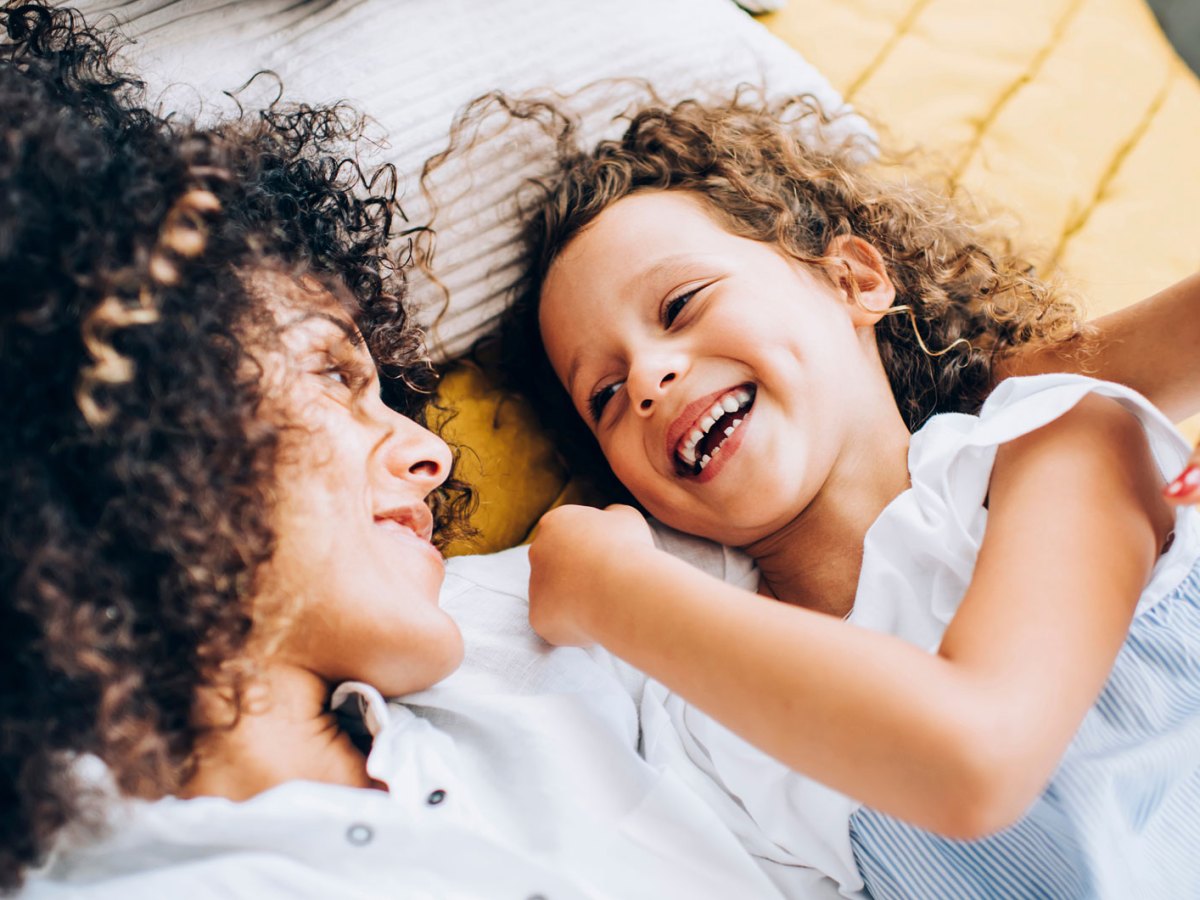 Mutter und Tochter kuschen und albern auf dem Bett herum.