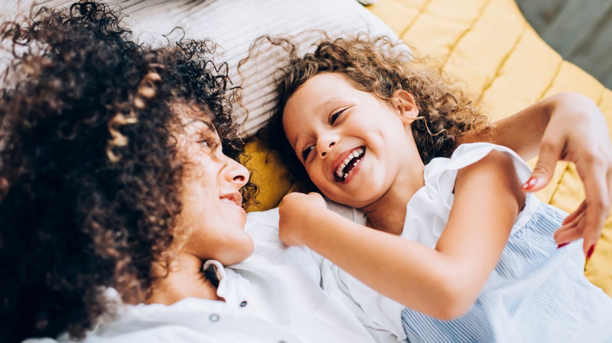 Mutter und Tochter kuschen und albern auf dem Bett herum.