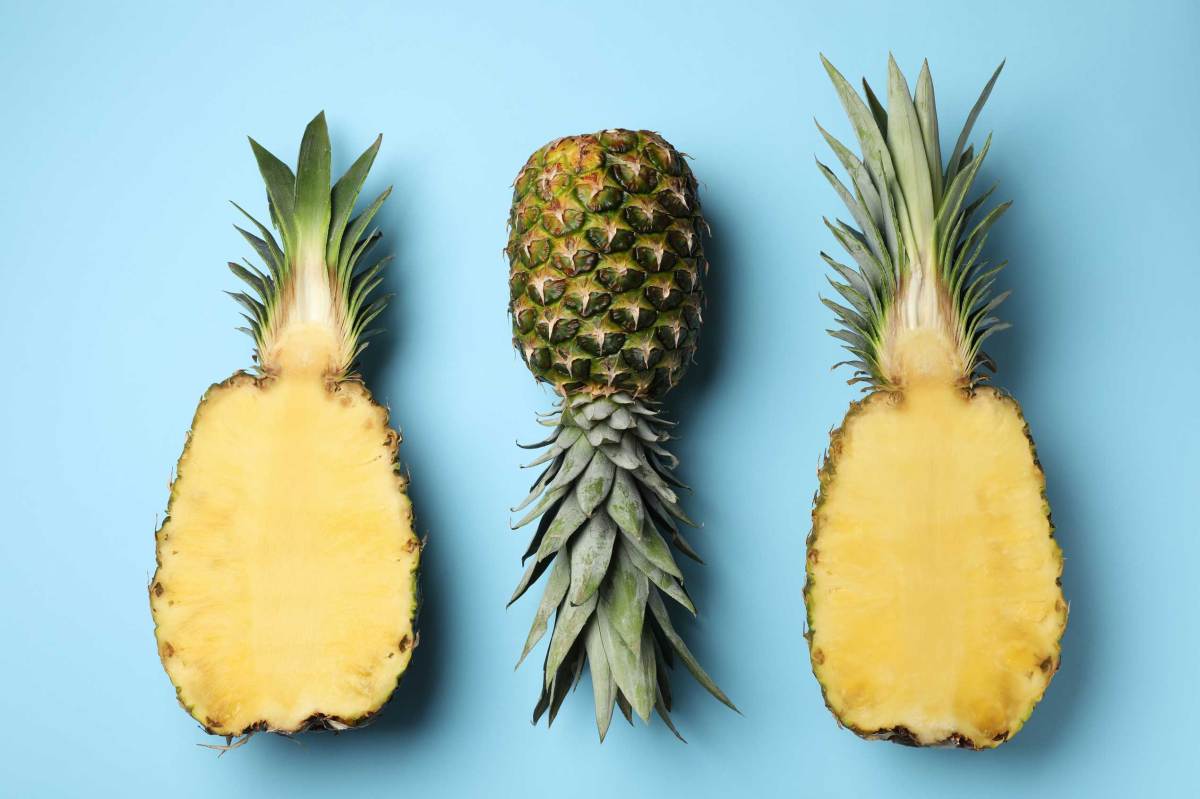 Frische ganze und geschnittene Ananas auf hellblauem Hintergrund, Ansicht von oben